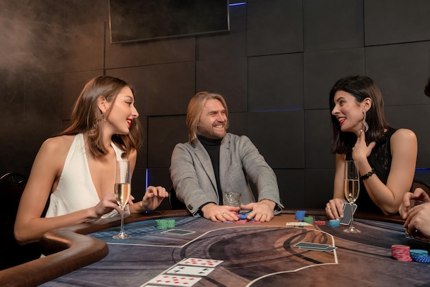 Cheerful man winning poker game and taking pot during friendly party