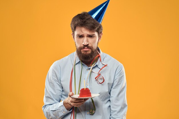 Cheerful man with a cake on a yellow background birthday holidays cap on his head person