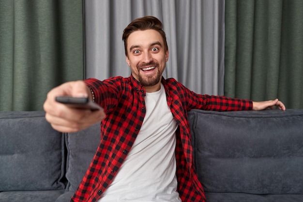 Cheerful man with remote control watching movie