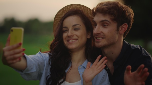 Cheerful man and woman call video online on mobile phone in summer park