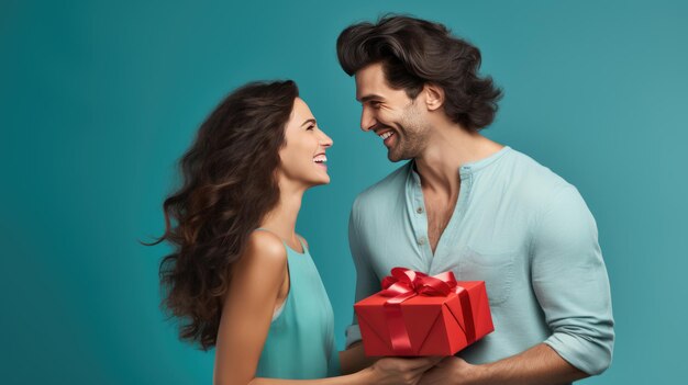 Cheerful man and woman closely facing each other smiling joyfully while holding a red gift between them