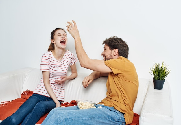 Foto uomo e donna allegri sul divano con popcorn e fiori a quadri rossi in un vaso di emozioni