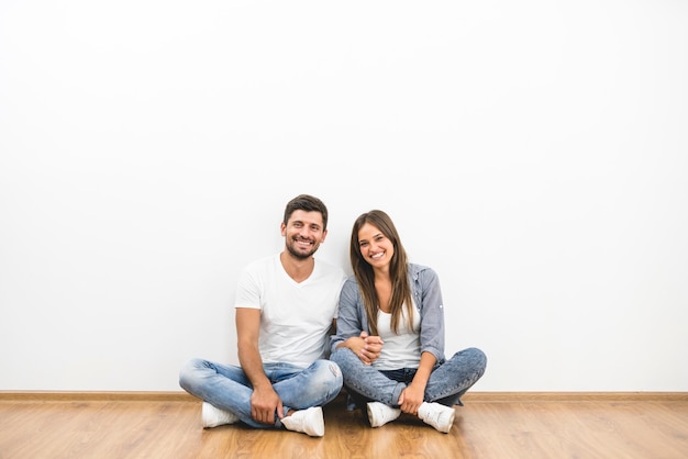 The cheerful man and woman sit near the empty wall