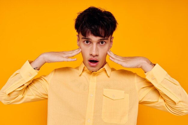 Cheerful man in yellow shirt posing fashion gesture with hands