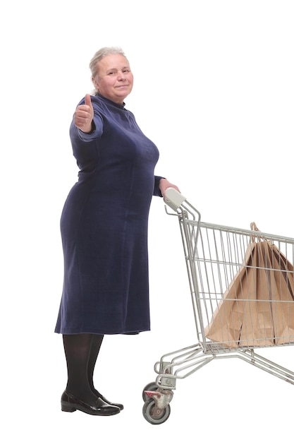 Cheerful mature lady with a shopping cart giving a thumb up