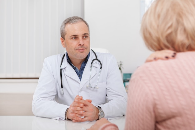 Cheerful mature male doctor talking to a patient