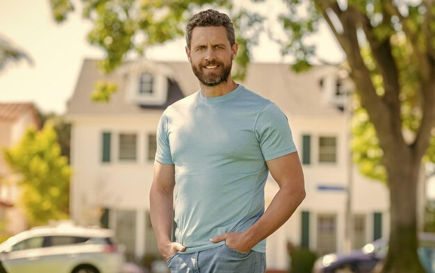 Cheerful mature man standing outdoor at house customer