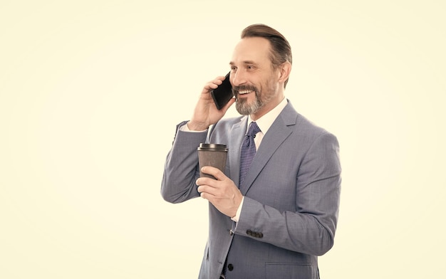 Cheerful mature man in suit talking on phone and drink coffee isolated on white conversation