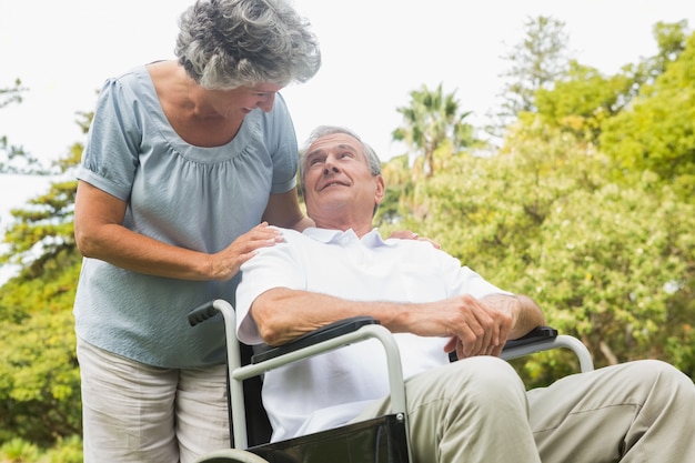 Cheerful mature man in wheelchair talking with partner