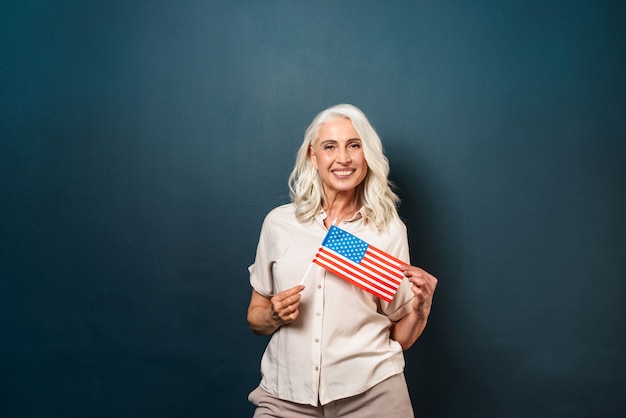 Cheerful mature old woman holding USA flag.