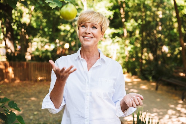 Cheerful mature woman holding green apple