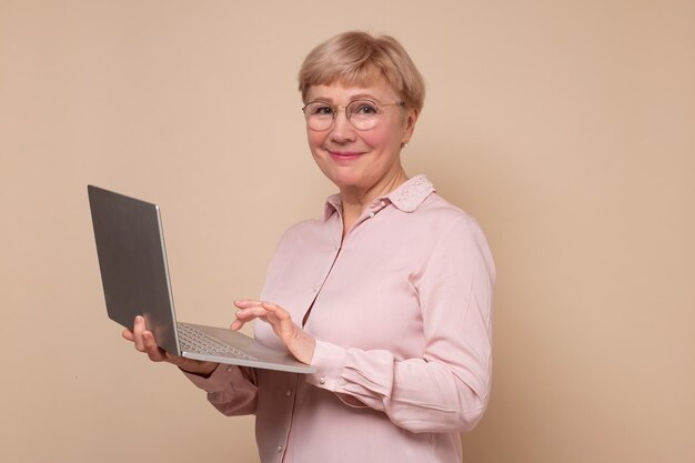 Cheerful mature woman standing with laptop computer smiling