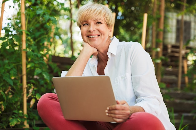 Donna matura allegra che per mezzo del computer portatile