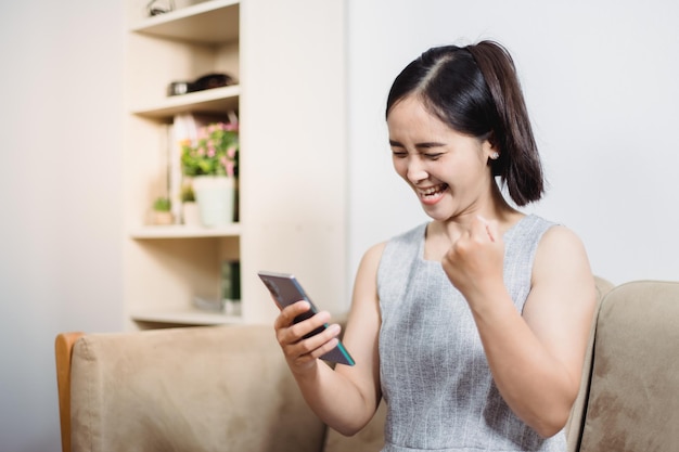 Cheerful mature woman using smartphone working at home office