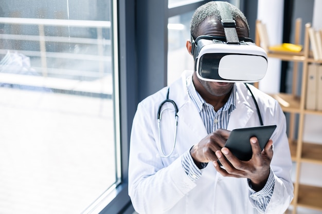 Веселый медицинский работник в маске для виртуального зрения и наслаждается процессом ее использования