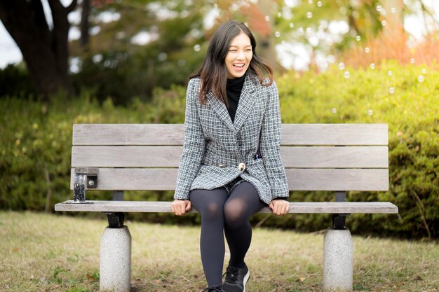 Photo cheerful mid adult woman sitting on bench in park