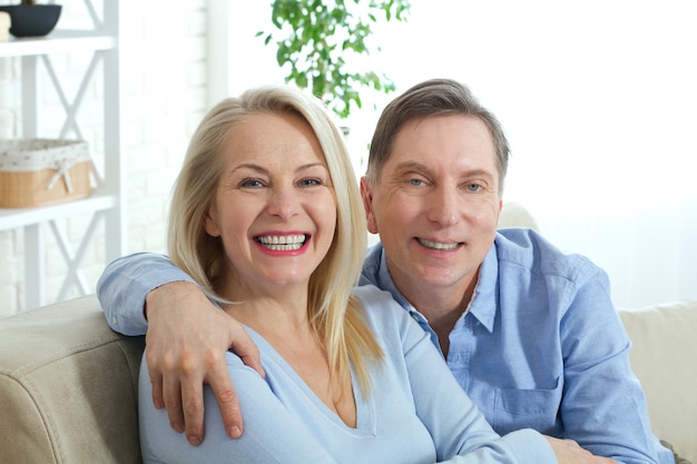 Cheerful middle aged couple in an embrace in living room.