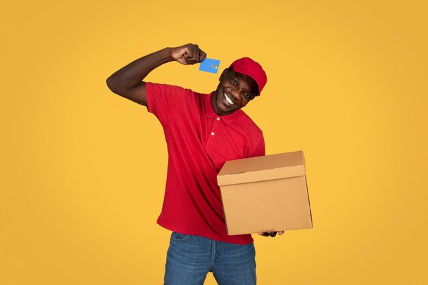 Cheerful millennial african american guy courier hold box recommends credit card