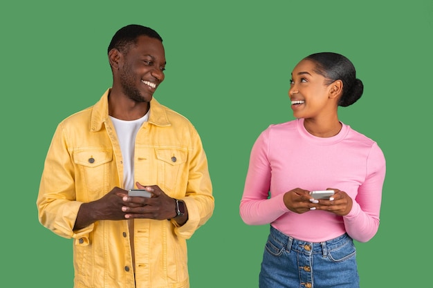 Cheerful millennial african american lady and guy typing on phone