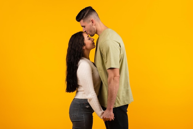 Cheerful millennial arab tall husband kissing wife on forehead couple enjoy free time and tender moment