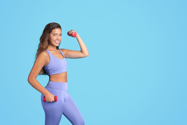 Cheerful millennial caucasian slim lady in sportswear do exercises with hand dumbbells enjoy weight
