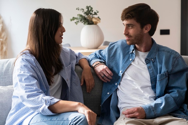 cheerful millennial interracial lovers enjoying time together at home happy arab man and indian woman sitting on couch in living room embracing and having conversation love family relationship