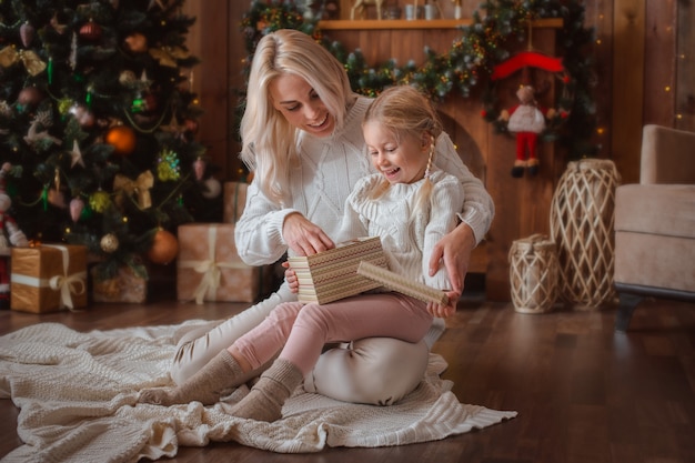 Cheerful mom and her cute daughter girl exchanging gifts