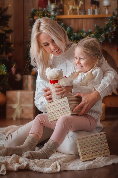 Cheerful mom and her cute daughter girl exchanging gifts
