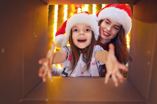쾌활한 엄마와 그녀의 귀여운 딸 소녀는 크리스마스 선물을 열어