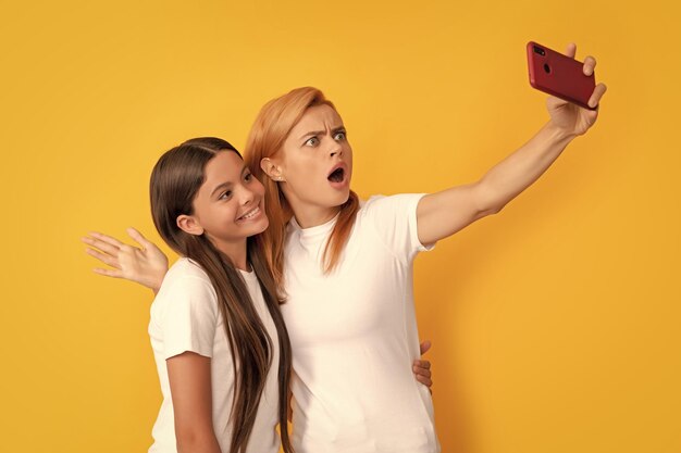 Cheerful mom and kid making selfie on smartphone shooting vlog
