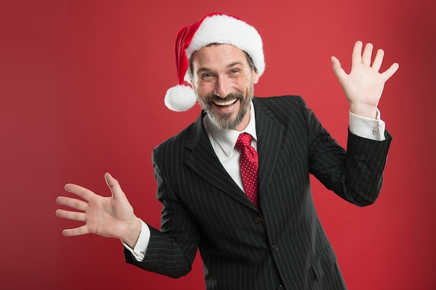 Umore allegro. avvio di un'attività che ruota intorno al periodo natalizio. affari e società. concetto di festa di natale. uomo con barba in abito elegante e cappello da babbo natale. l'uomo d'affari celebra il natale.