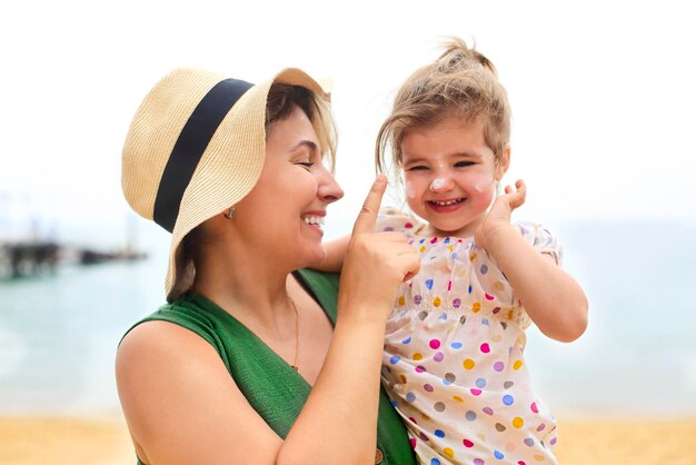 Photo cheerful mother applying moisturizer on daughters face