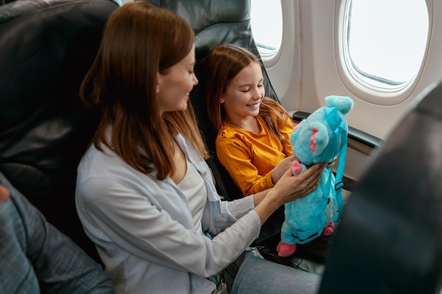 飛行機の中でおもちゃで遊ぶ元気な母と娘