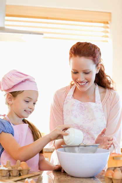 Cheerful mother and daughter preparing dough