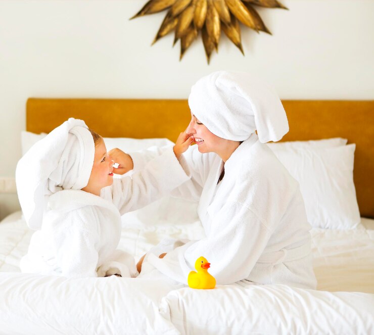 Photo cheerful mother and daughter touching nose on bed at home