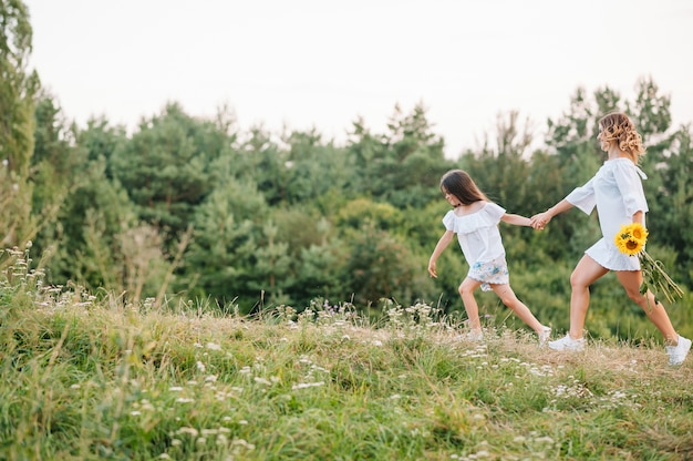 Cheerful mother and her little daughter having fun together in the summer surface