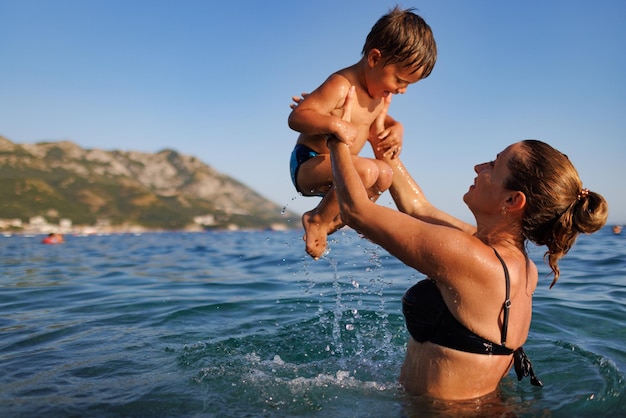 Cheerful mother plays with her son in the sea