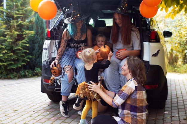 Photo cheerful mothers with kids playing by car