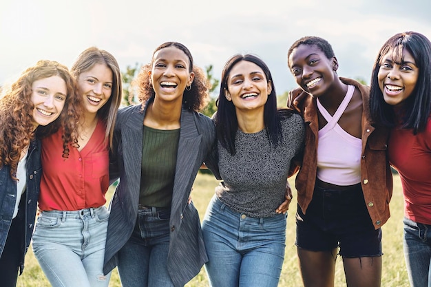 Cheerful multiethnic group of young women hugging arms on shoulders