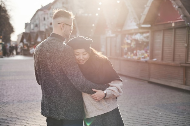 Photo cheerful multiracial couple embracing each other outdoors in the city. asian girl with her caucasian boyfriend.