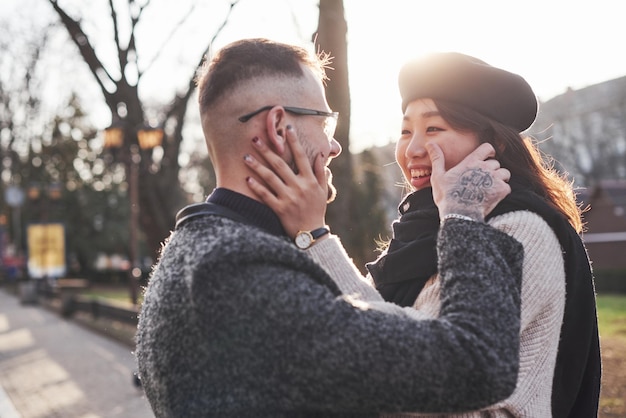 Cheerful multiracial couple embracing each other outdoors in the city. Asian girl with her caucasian boyfriend.