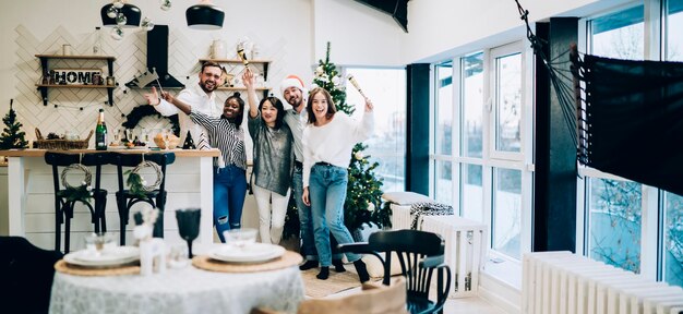 Photo cheerful of multiracial gathering of women and men posing celebrating christmas looking at camera