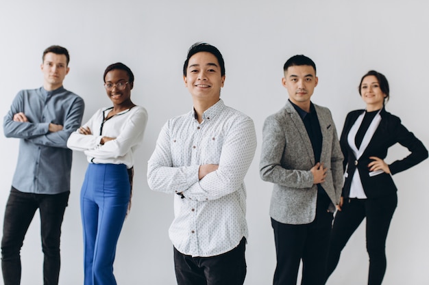 Cheerful multiracial professional business people laughing together standing in row near wall, happy diverse young employees students group, corporate staff team having fun, human resource concept