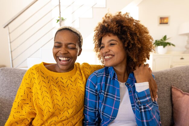 Cheerful multiracial young lesbian couple relaxing on sofa in living room