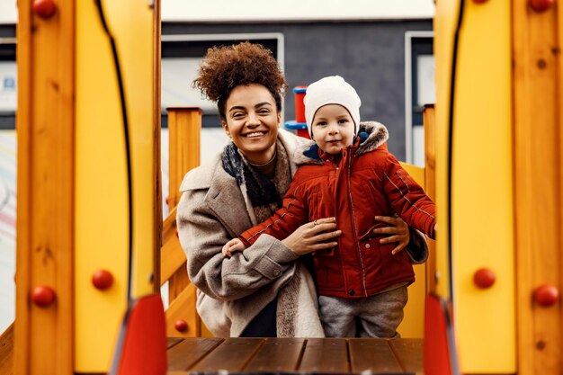 A cheerful nanny taking care of a little boy at outdoor playground