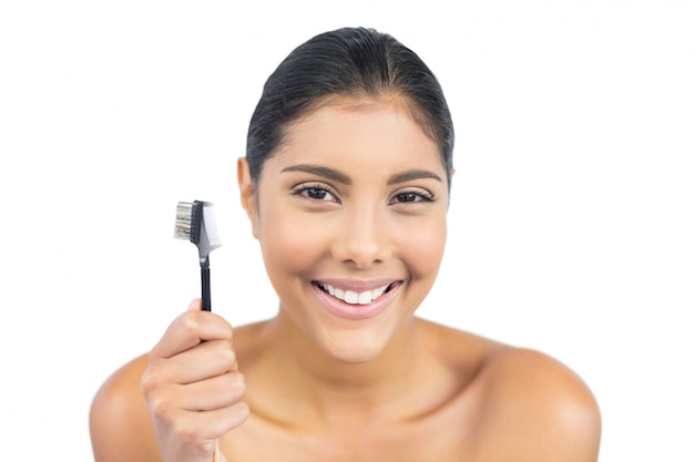 Cheerful nude brunette holding eyebrow brush