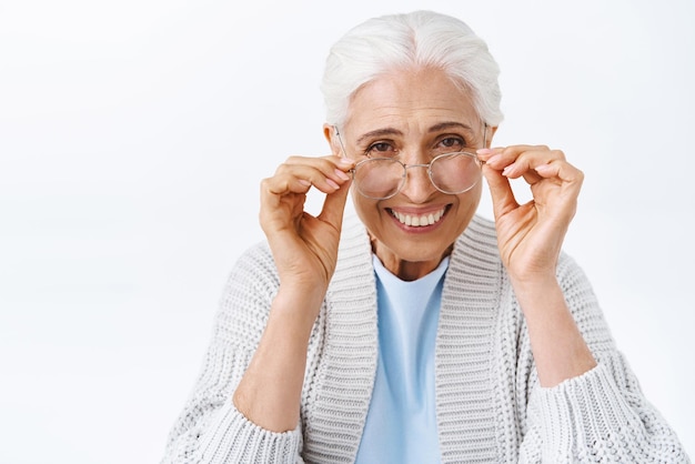 Cheerful old charming woman happy grandmother put on glasses to read book child touching eyewear and smiling laughing joyfully pick prescription glasses at optician store for better vision