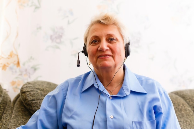 Photo cheerful old senior woman looking at camera at home, smiling elderly grandmother blogger sit on sofa communicating in online chat making distance conference video call recording vlog, webcam view