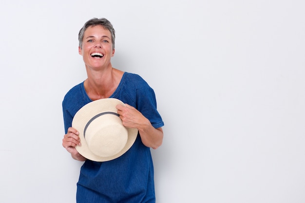 Cheerful older woman laughing with hat against white backgorund