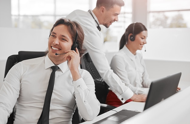 Cheerful operator speaking with client near colleagues